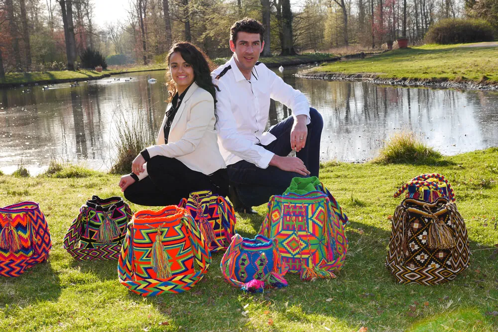 Adam und Catalina Sikora sitzen am Seeufer, vor ihnen mehrere Mochilas im Gras